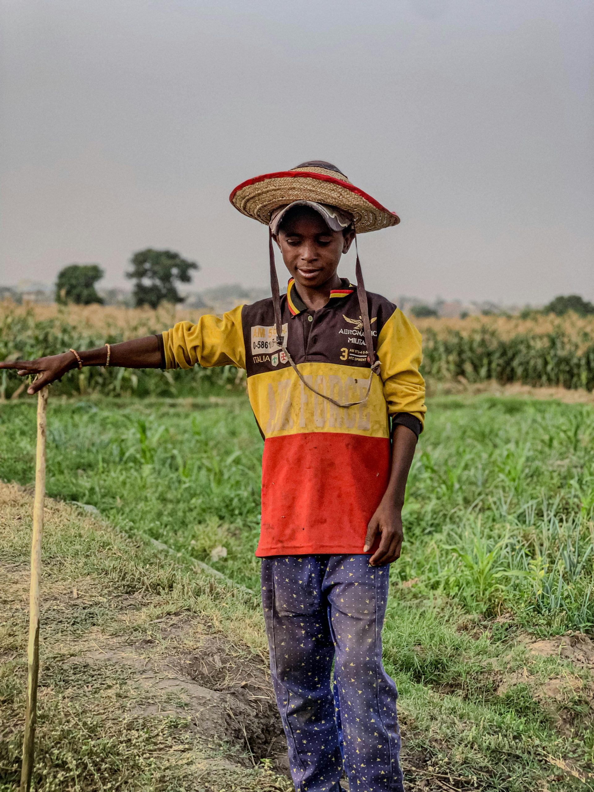 A young farmer stands in a lush field in Kaduna South, Nigeria, showcasing traditional agricultural practices.